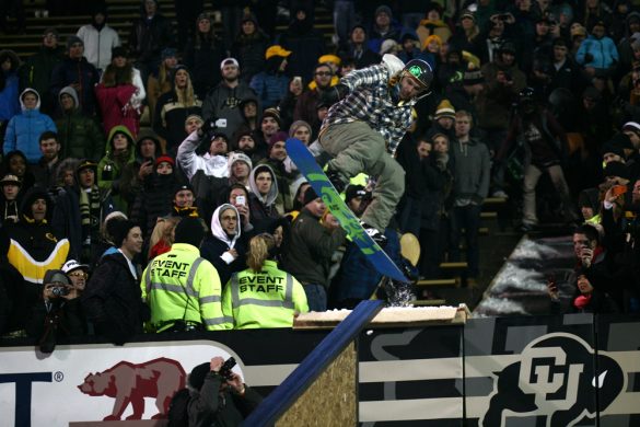 A member of the CU Snowboard Team jumps from the stands onto a rail during halftime. (James Bradbury/CU Independent)