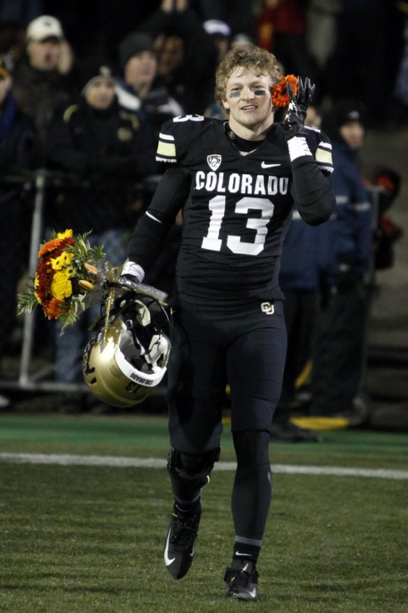 Senior defensive back Parker Orms (13) jokingly puts a flower in his ear while running onto the field during a senior ceremony. (Robert R. Denton/CU Independent)