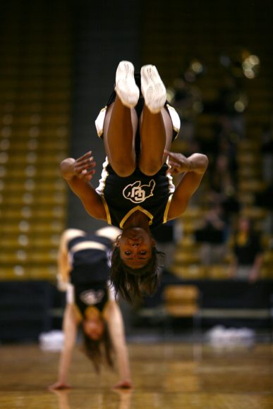 A CU cheerleader does a backflip across the court during a timeout. (Kai Casey/CU Independent)