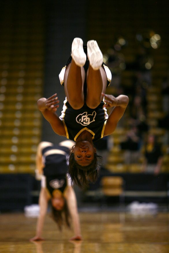 A CU cheerleader does a backflip across the court during a timeout. (Kai Casey/CU Independent)