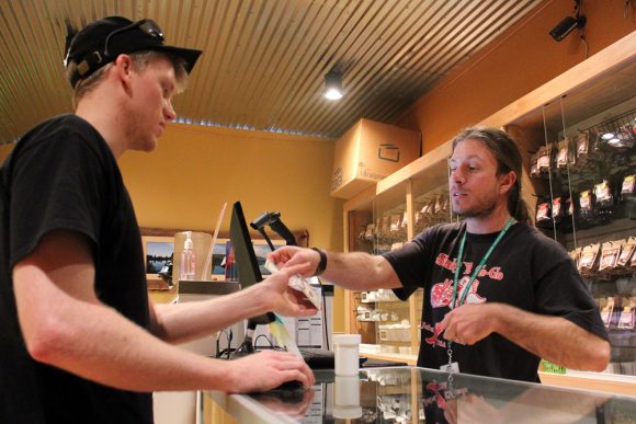 Justin Lapenter, right, a bud tender, gives Chris Horner, a Colorado State graduate who now lives in Niwot, change back after Lapenter bought his first legal recreational weed. (Kai Casey/CU Independent)