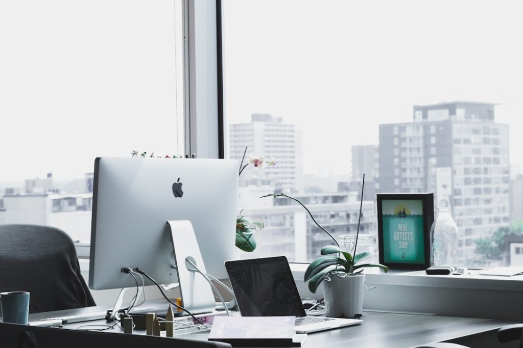 A desk setup with a computer, a laptop, and a plant, illustrating top tools for knowledge management effectively.