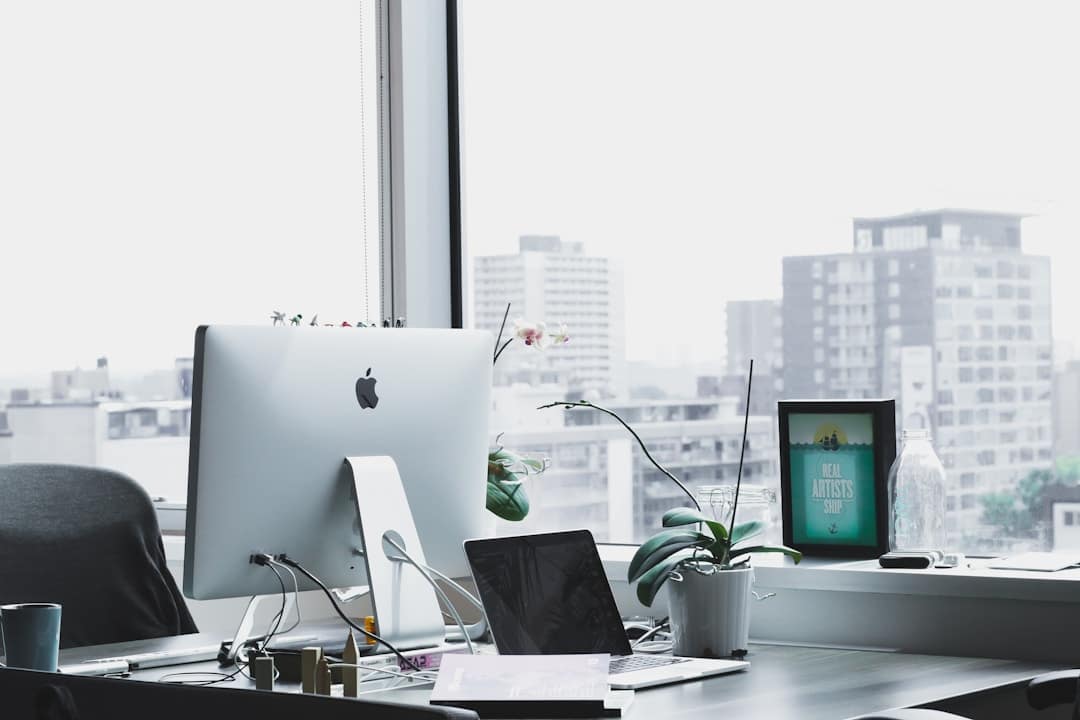 A desk setup with a computer, a laptop, and a plant, illustrating top tools for knowledge management effectively.