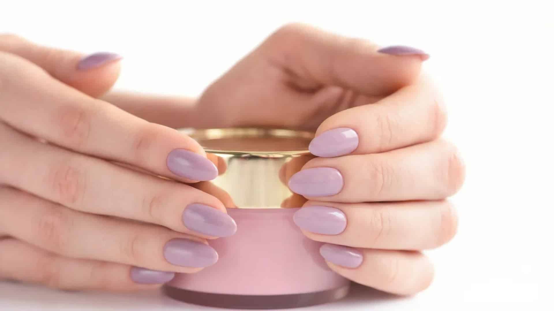 Hands with glossy lavender dip nails holding a small jar