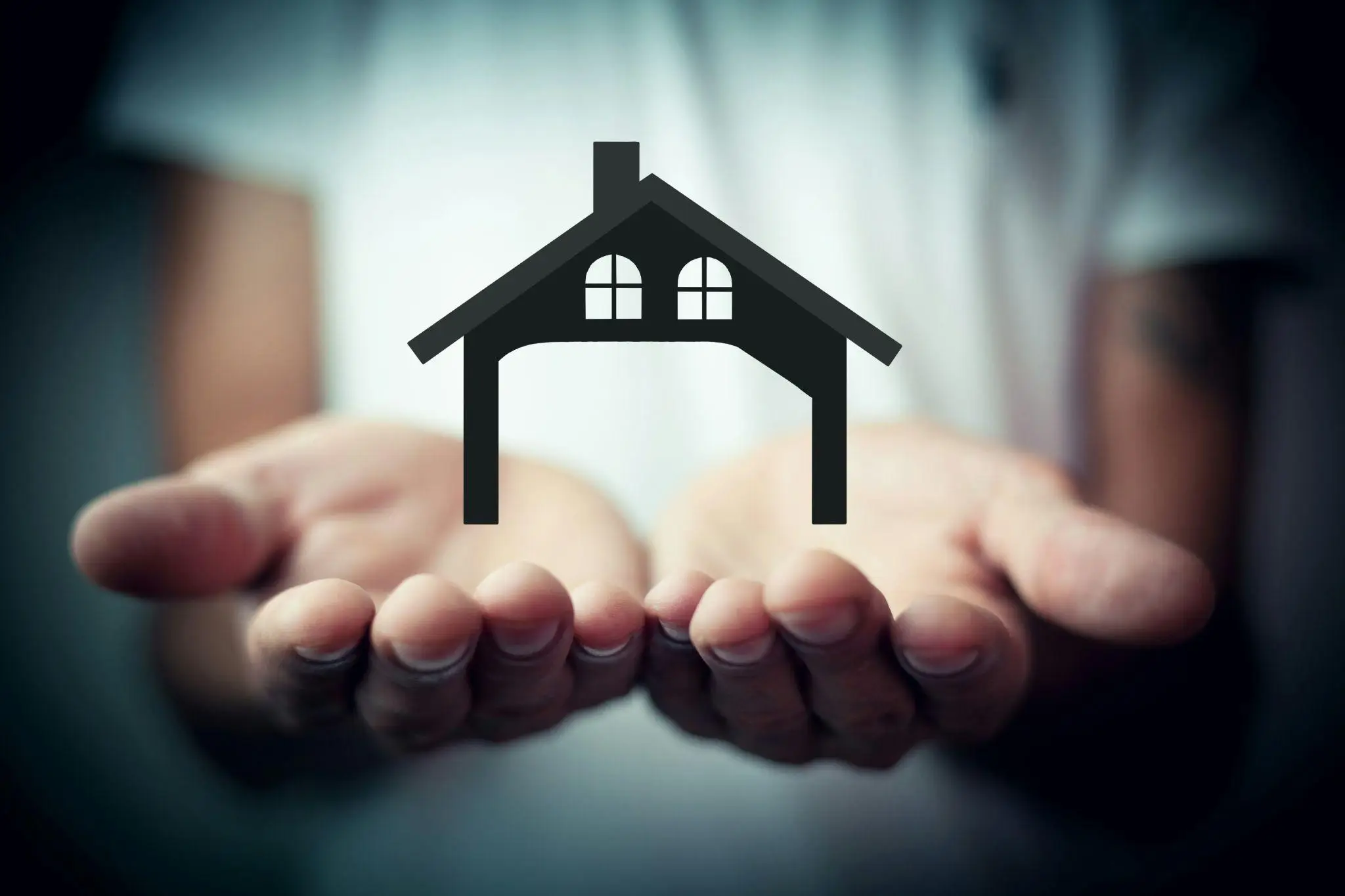 Hands holding a house icon with soft focus background