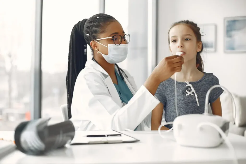 Doctor in white coat and mask checking young girl's breathing with a medical device indoors