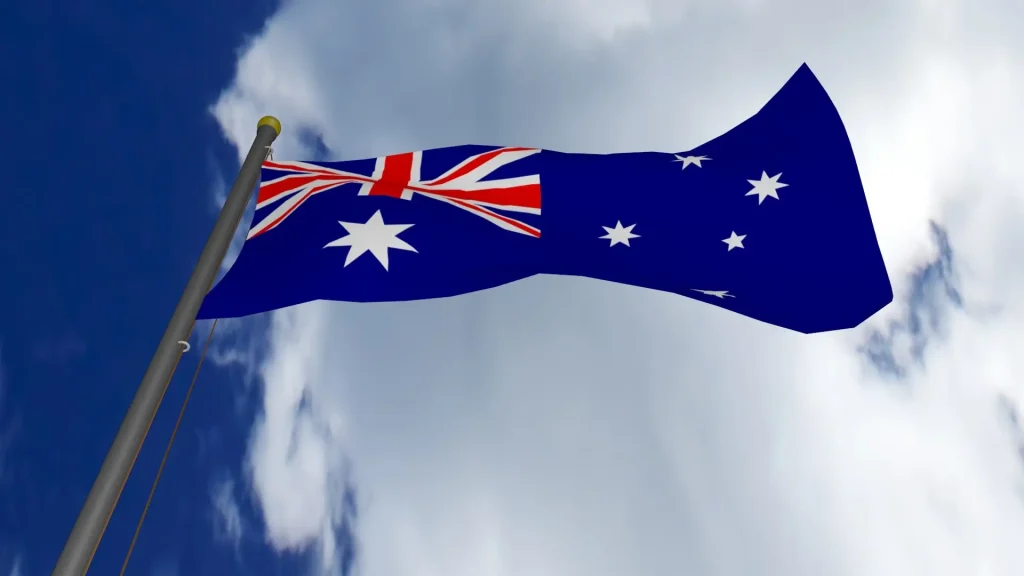 Australian flag waving against a bright blue sky with clouds