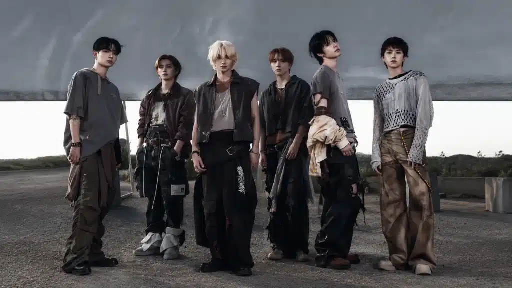 BOYNEXTDOOR six members standing outdoors, wearing casual street-style outfits with a neutral background.