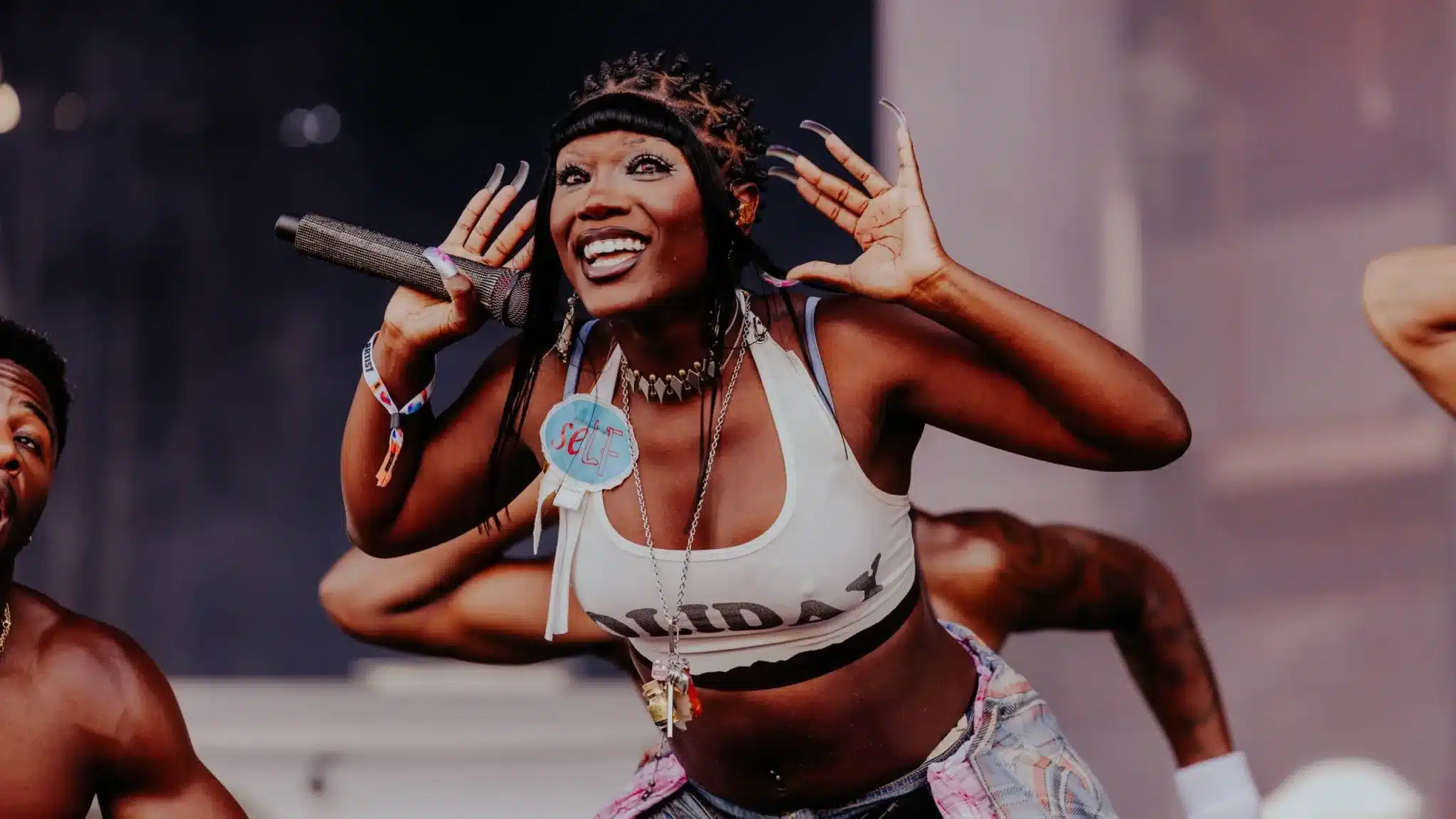Doechii performing live on stage with a microphone, energetic pose, and expressive crowd-hyping performance style