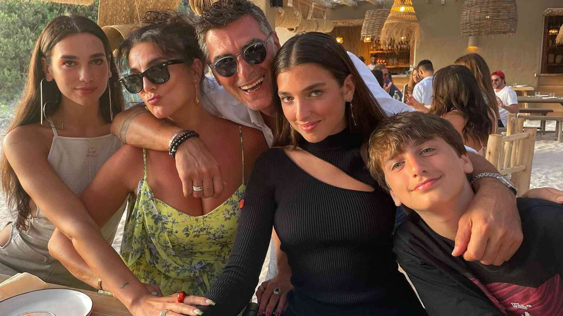 Dua Lipa posing with her family at a restaurant during a casual outdoor gathering