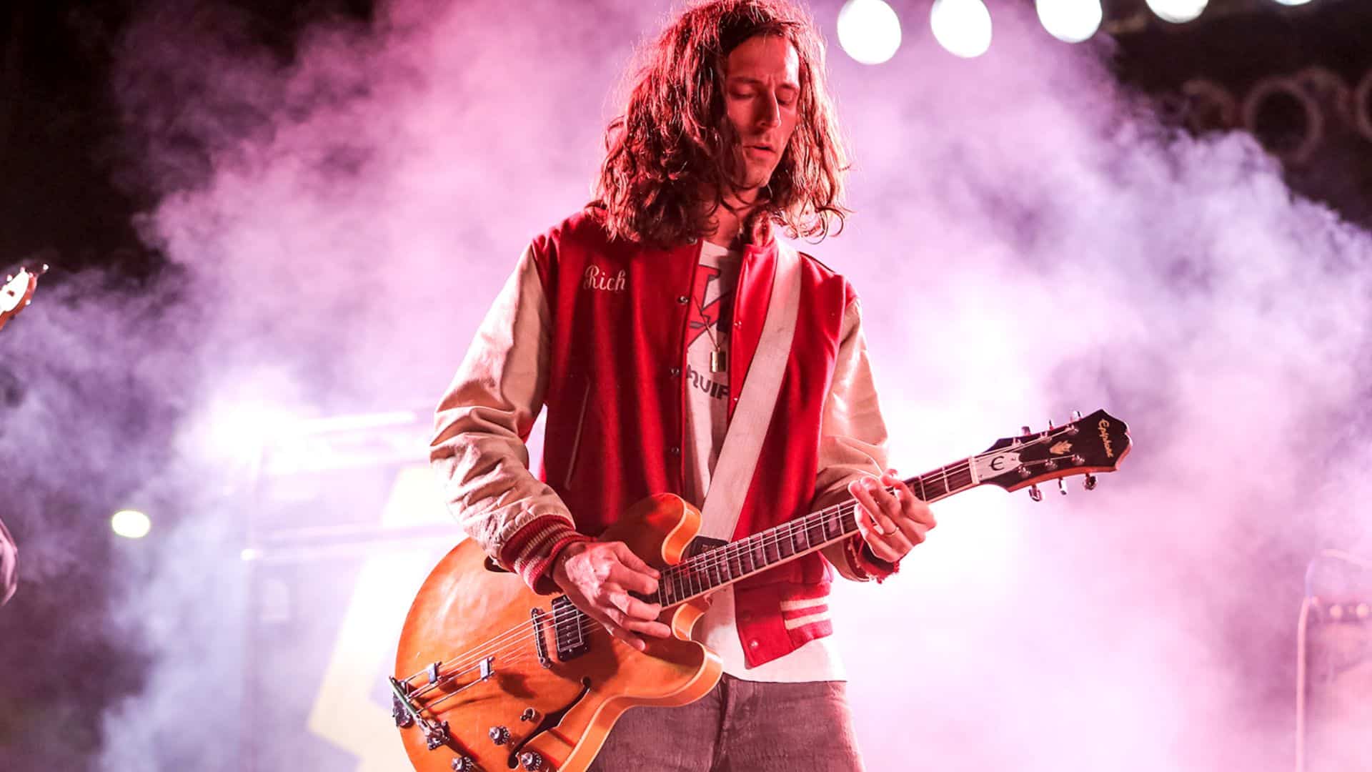 Nick Valensi, lead and rhythm guitarist of The Strokes, playing an Epiphone guitar on a smoke-filled stage