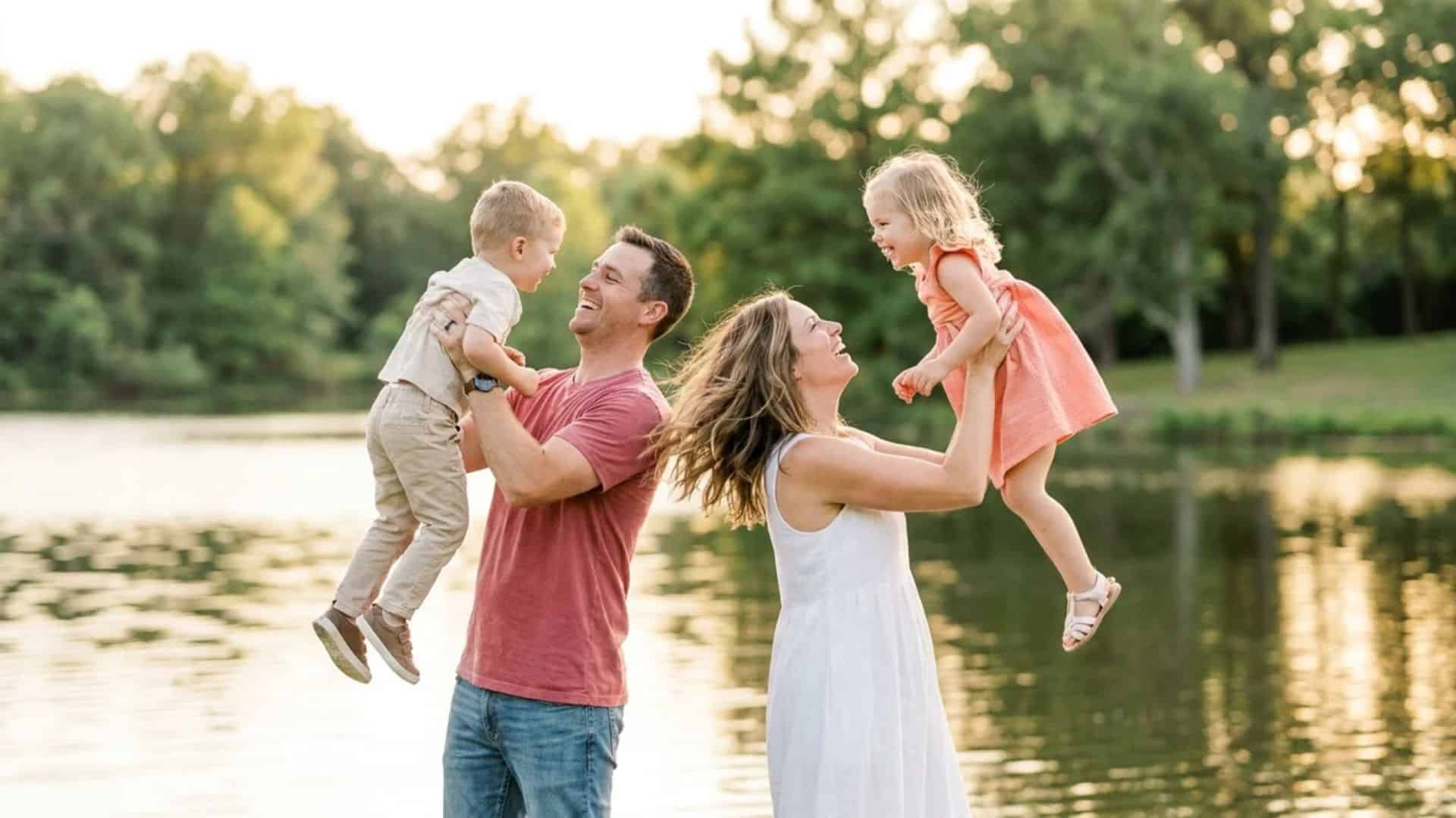 Parents lifting children near peaceful lake during outdoor family lifestyle photography session