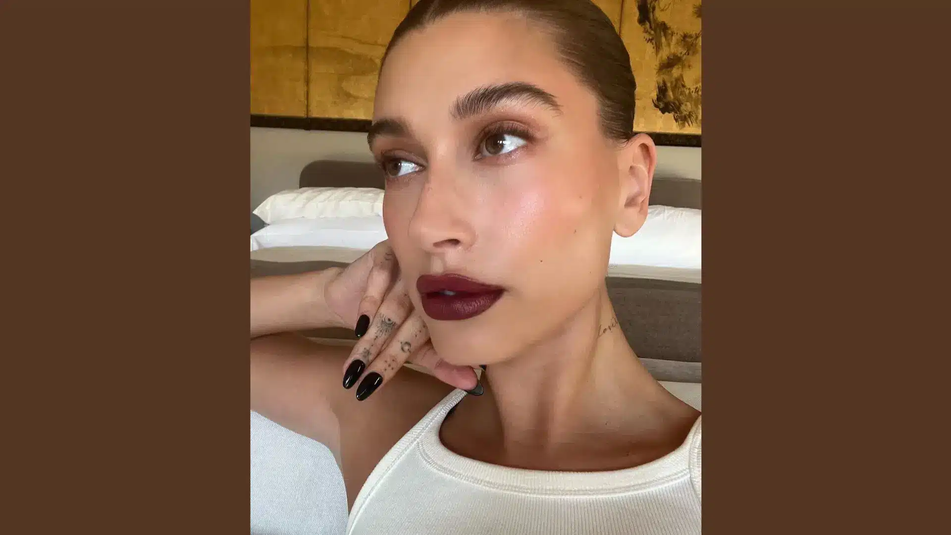 A person showing off Glossy Black Nails with a burgundy lip and visible tattoos