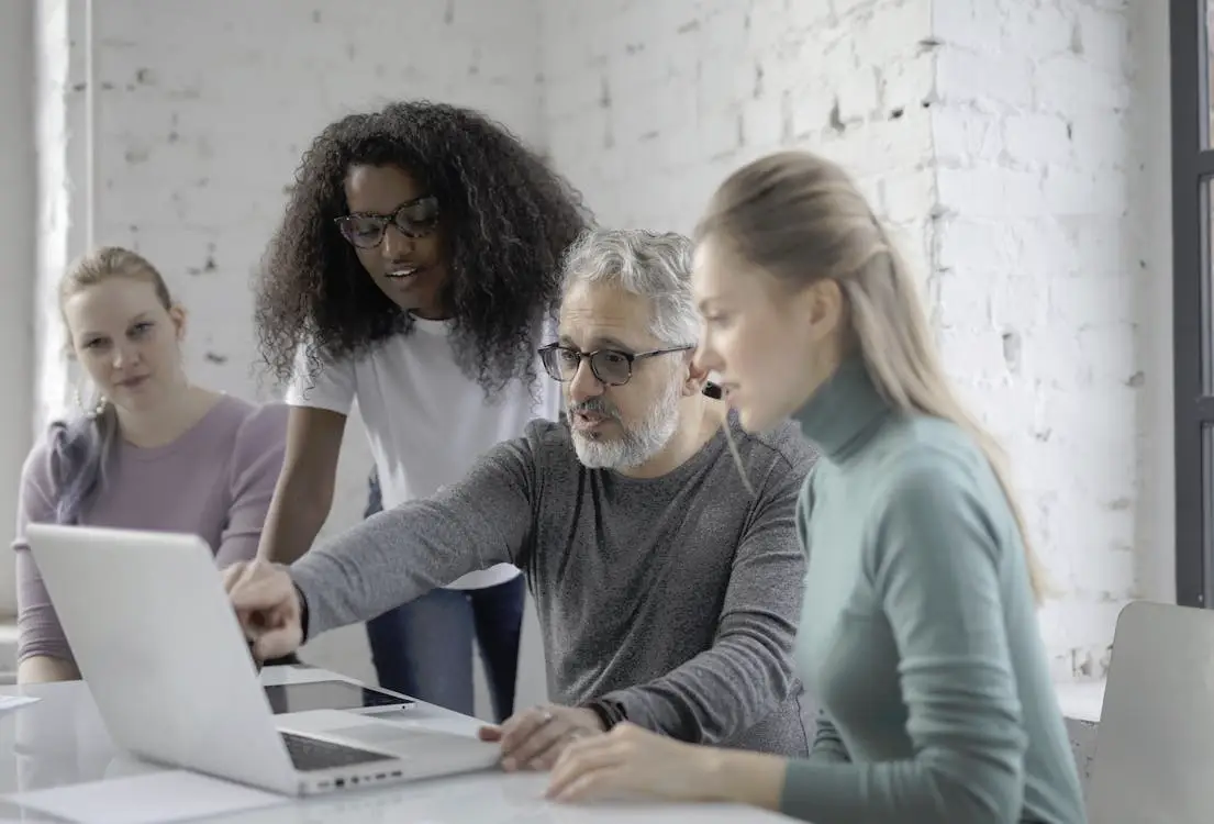 Group of people collaborating around a laptop in a bright office setting