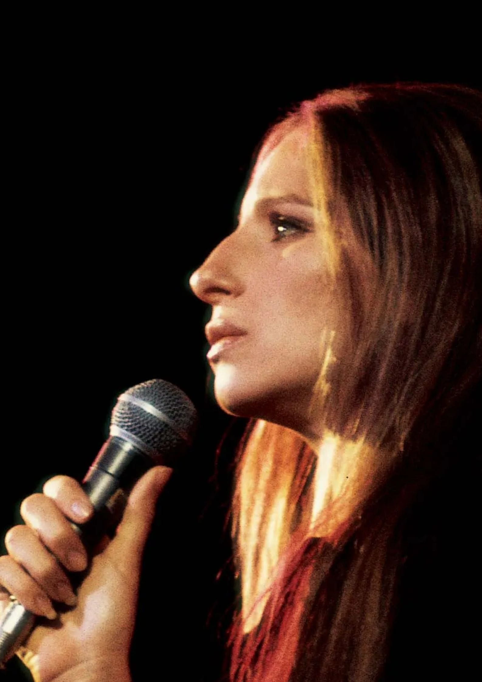 Barbra Streisand performing on stage with a microphone, American Jewish singer, actress, and director with a career spanning several decades (1)