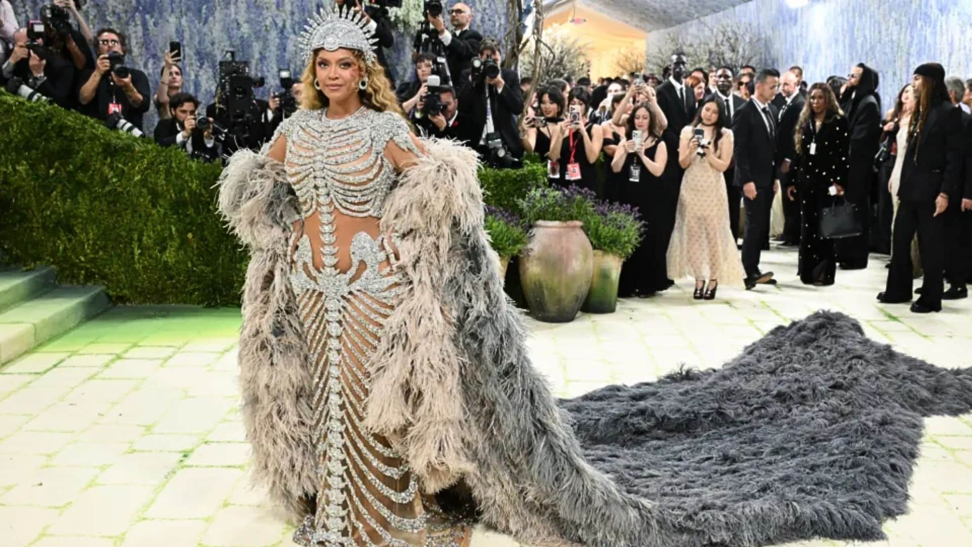 Beyoncé wearing a crystal-covered Olivier Rousteing gown with dramatic feathered cape and crown at the Met Gala