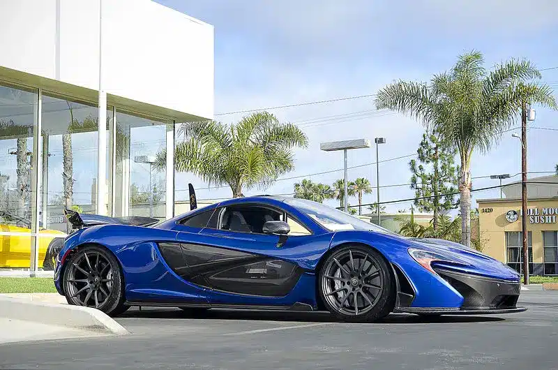 Blue McLaren P1 parked outside a luxury showroom with palm trees in the background