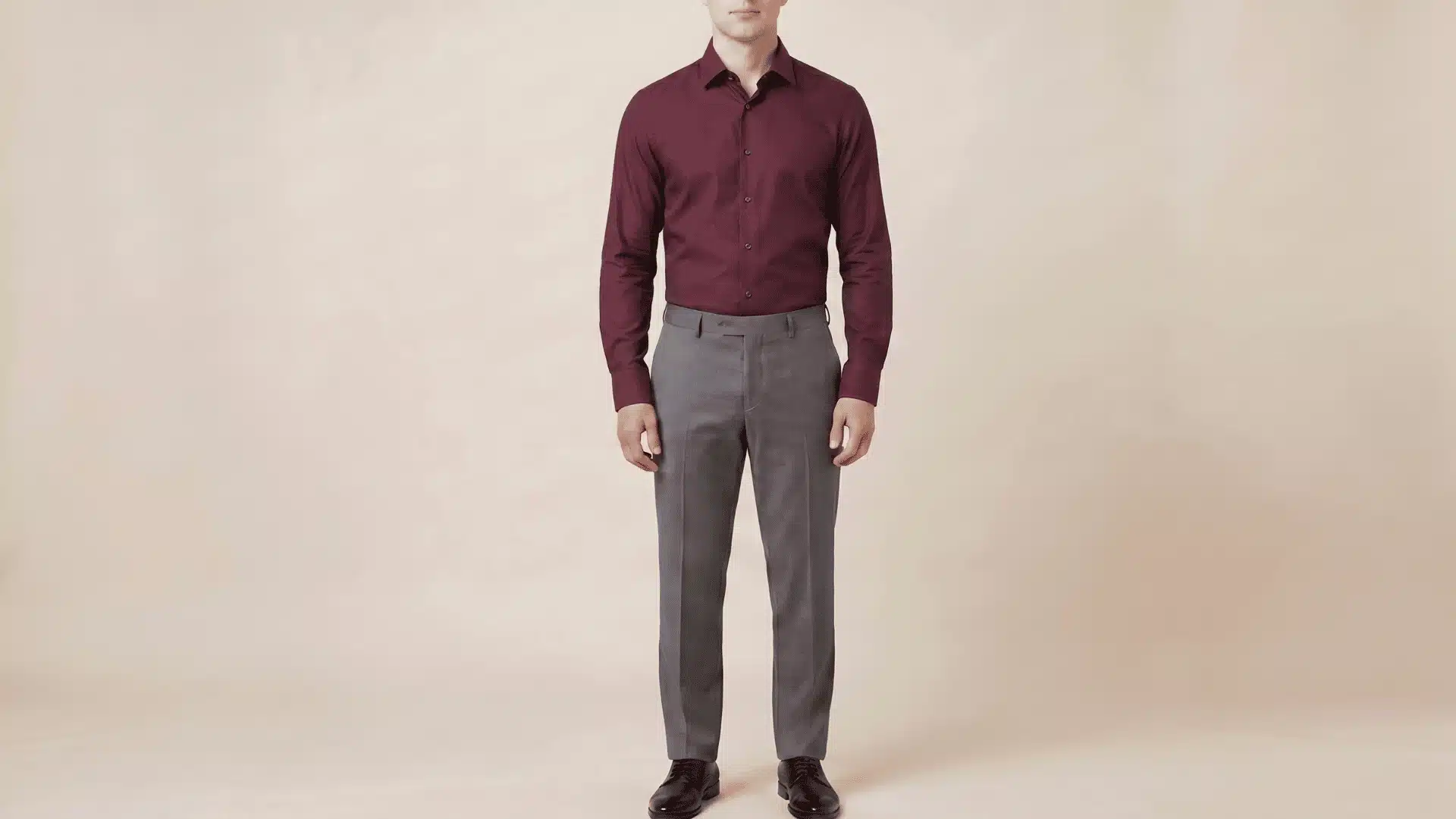 Man wearing a burgundy long-sleeve shirt with charcoal grey pants and black shoes, standing in a neutral background.