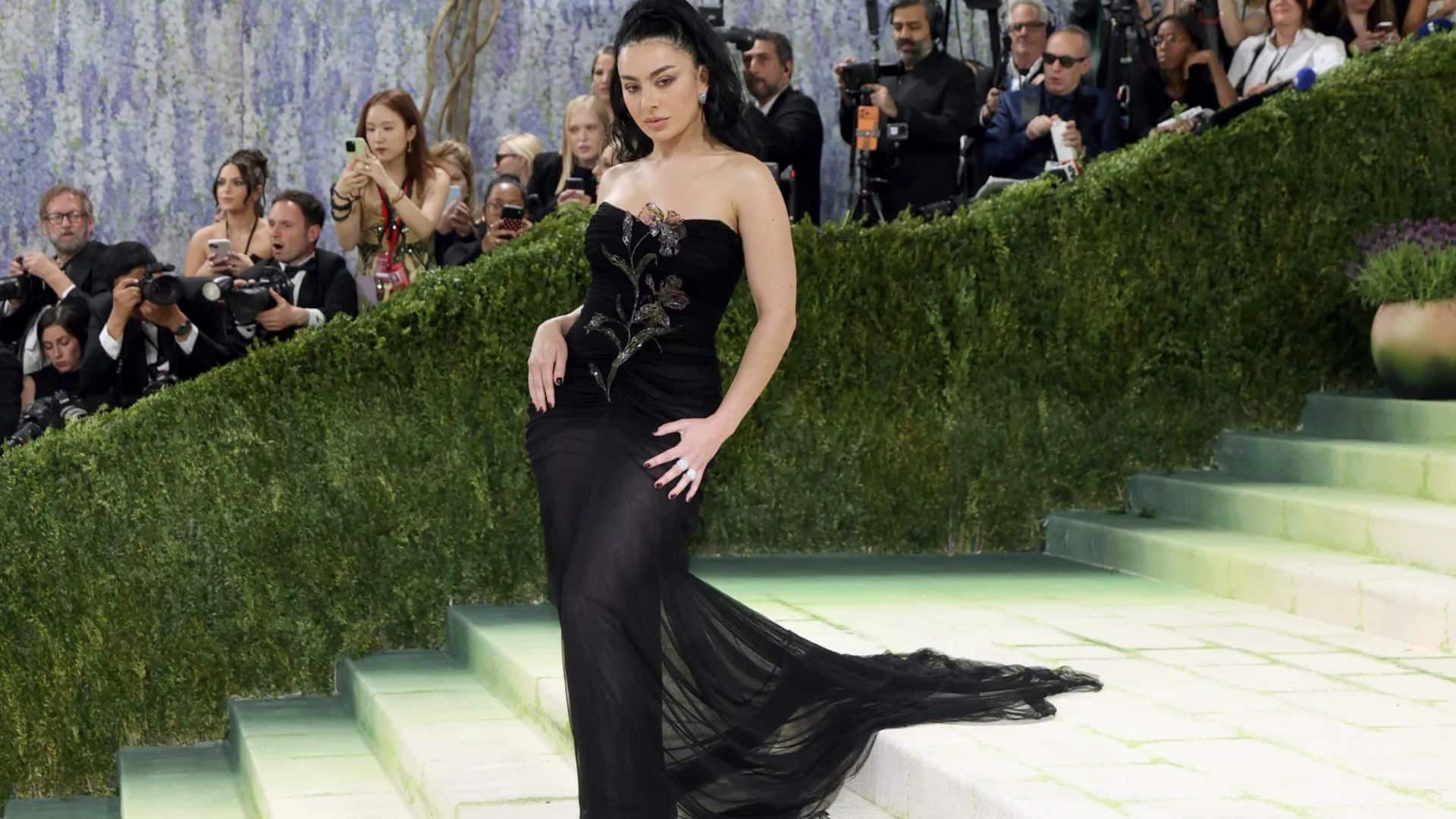 Charli XCX wearing a sheer black Saint Laurent gown with floral embellishments and flowing train
