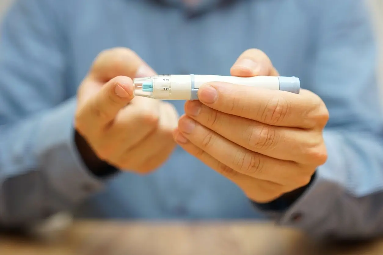 Hand holding a blood glucose meter in a close-up indoor shot