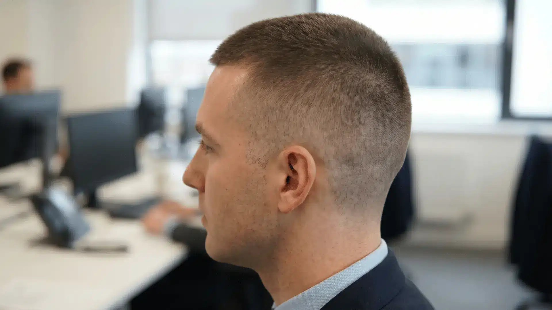 Short, clean crew cut on a male head in an office setting showing neat sides and top