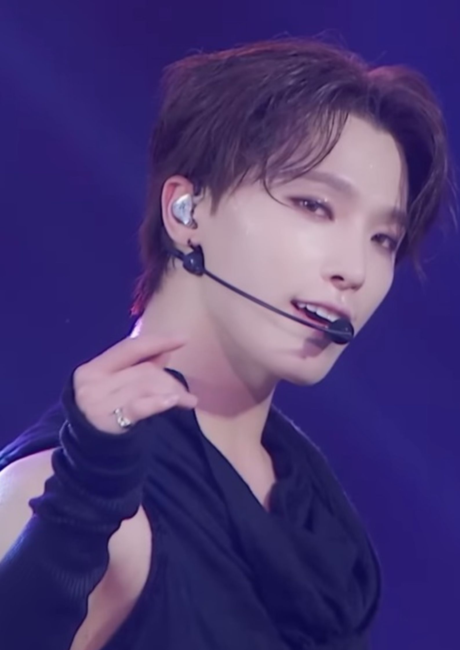 Dino of Seventeen performing on stage, wearing a black sleeveless outfit and headset microphone.