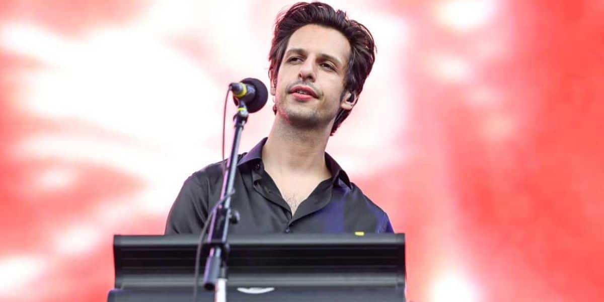 Edward James performing on stage, standing behind a keyboard with a microphone