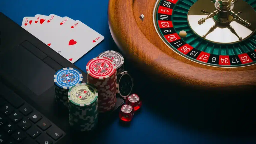 Roulette wheel with poker chips and playing cards on a blue felt table
