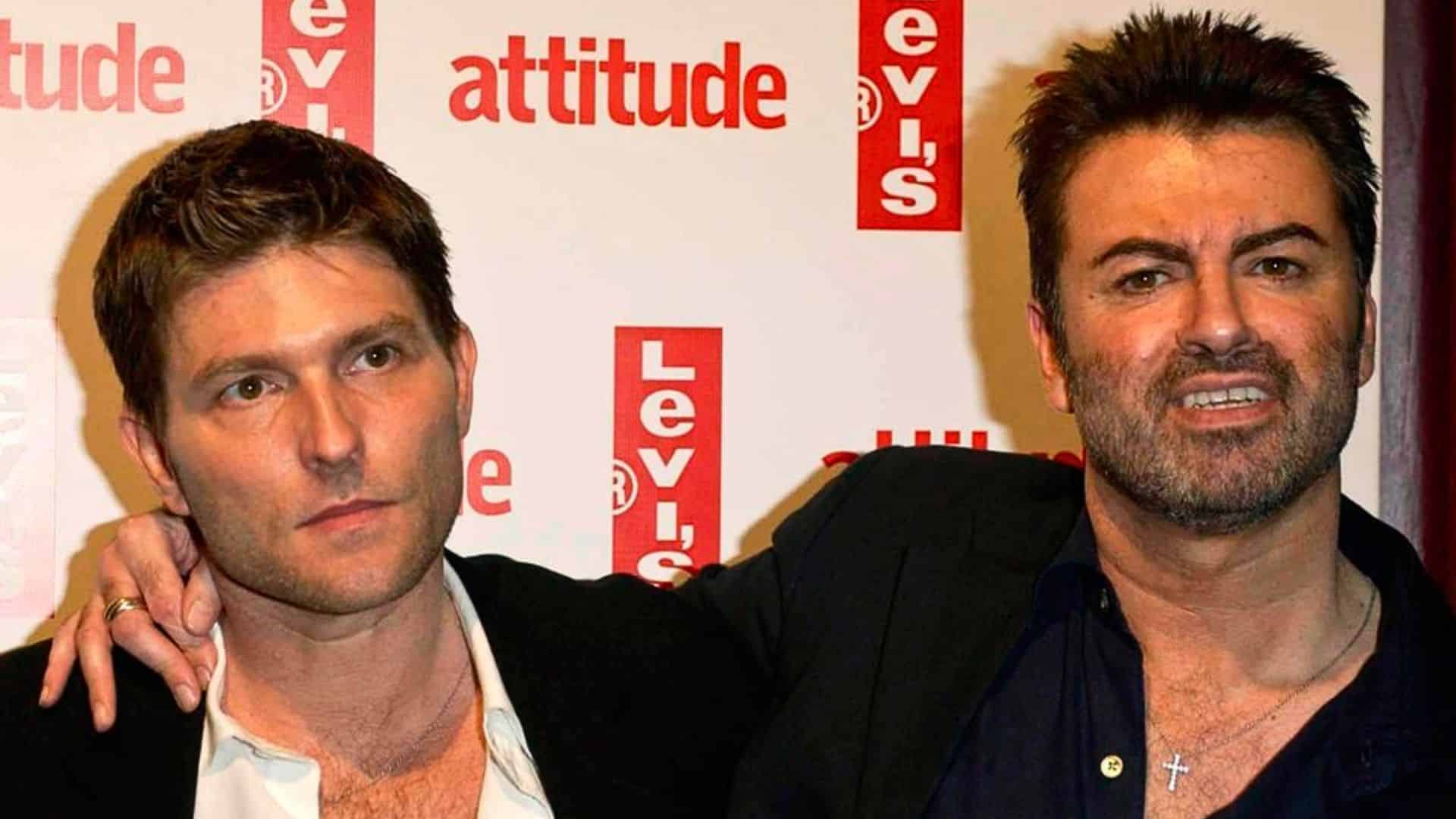 George Michael and Kenny Goss posing together at a public event with Levi’s and Attitude branding in the background