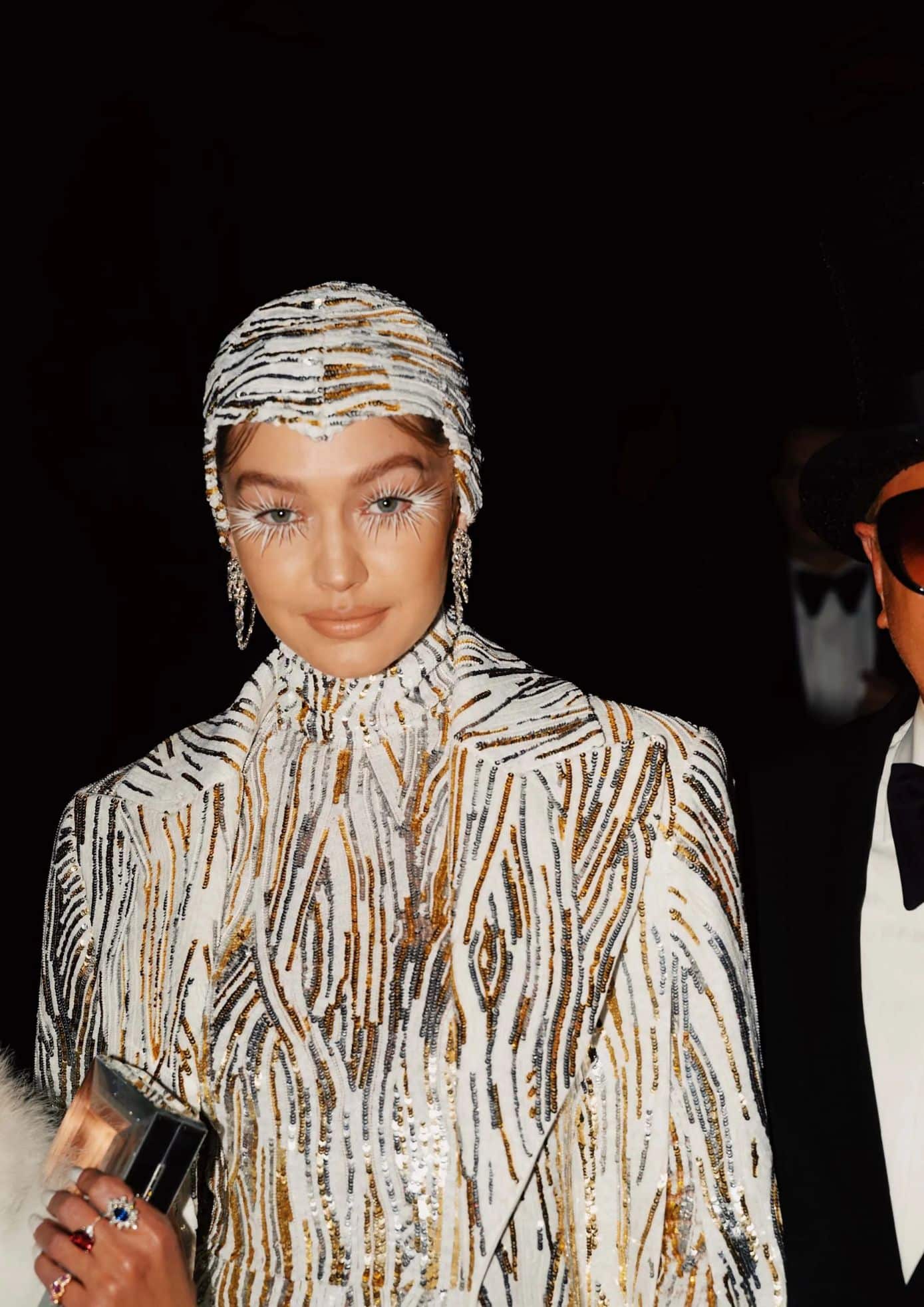 Gigi Hadid in a beaded white and gold outfit with dramatic lashes and headpiece. (1)