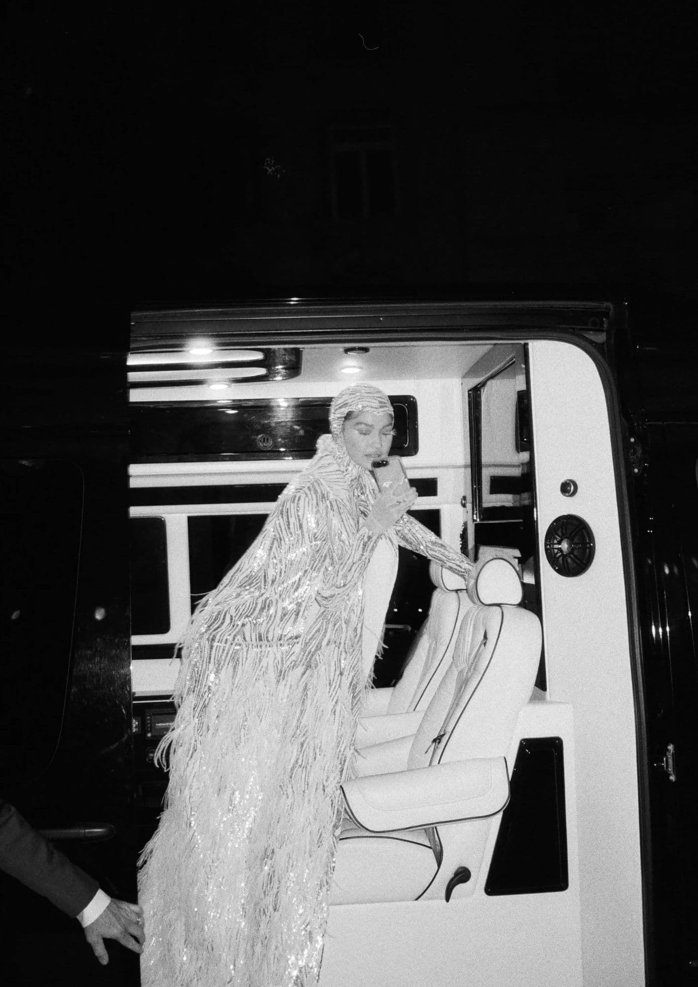 Gigi Hadid in a shimmering fringe gown, stepping out of a car with a phone in hand. (1)