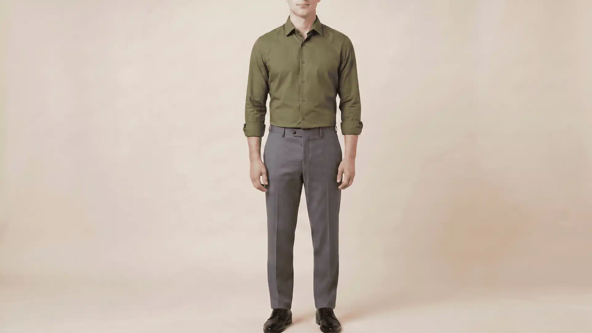 Man wearing a green long-sleeve shirt with charcoal grey pants and black shoes, standing in a neutral background.