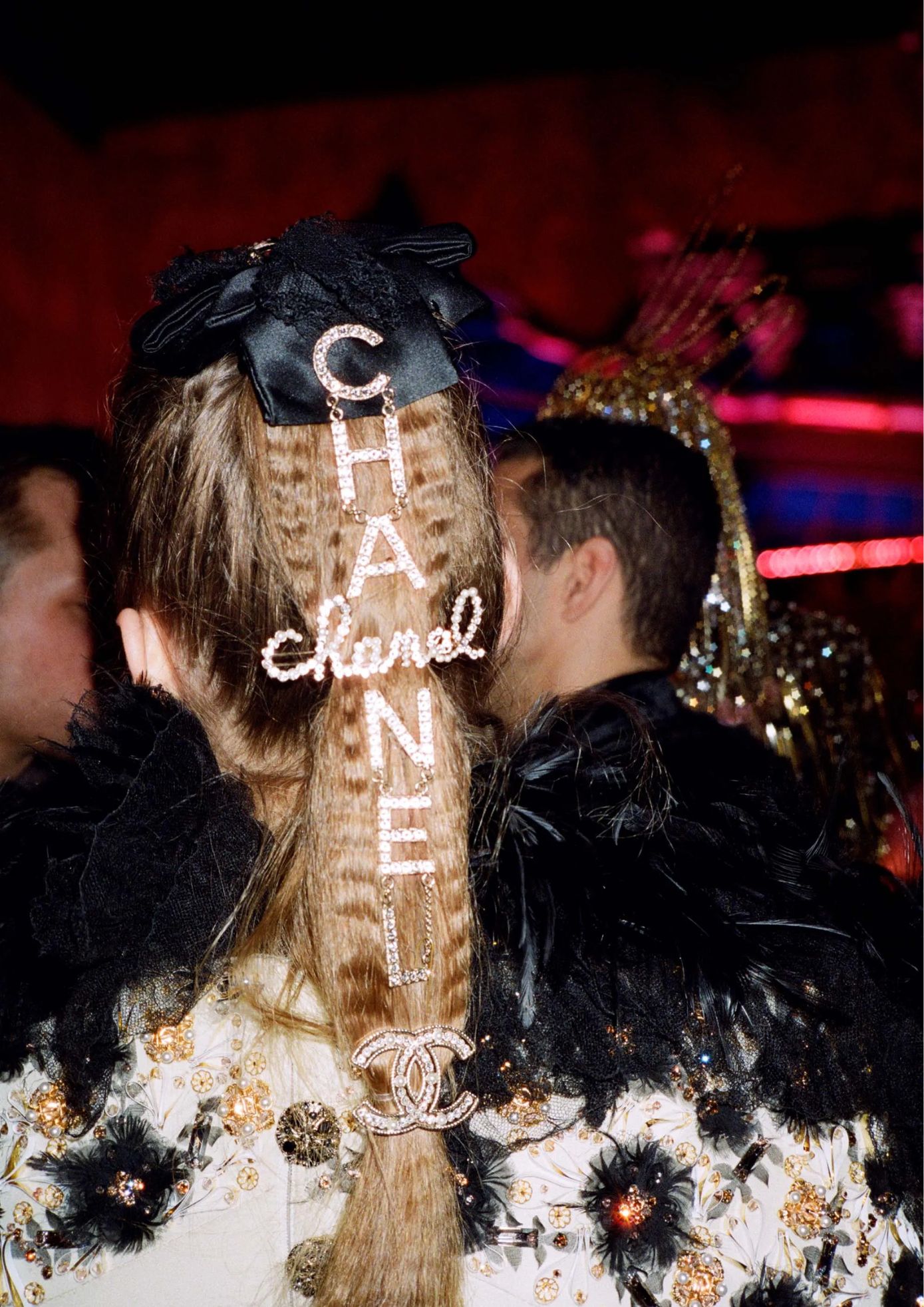 Guest with a Chanel-themed hairstyle featuring sparkling letters and logo clasp.