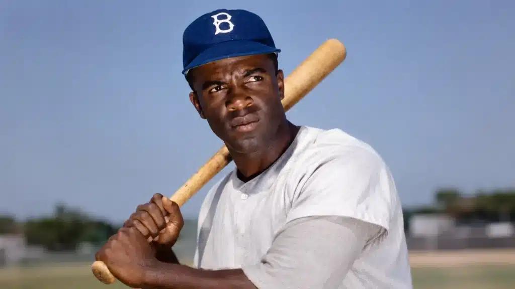Jackie Robinson in a vintage Brooklyn Dodgers uniform holding a baseball bat on a sunlit field