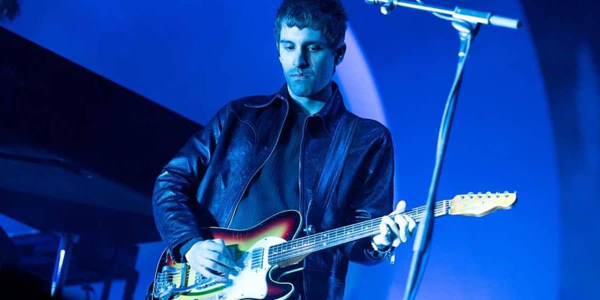 Jesse Perlman playing guitar on stage with a microphone in front