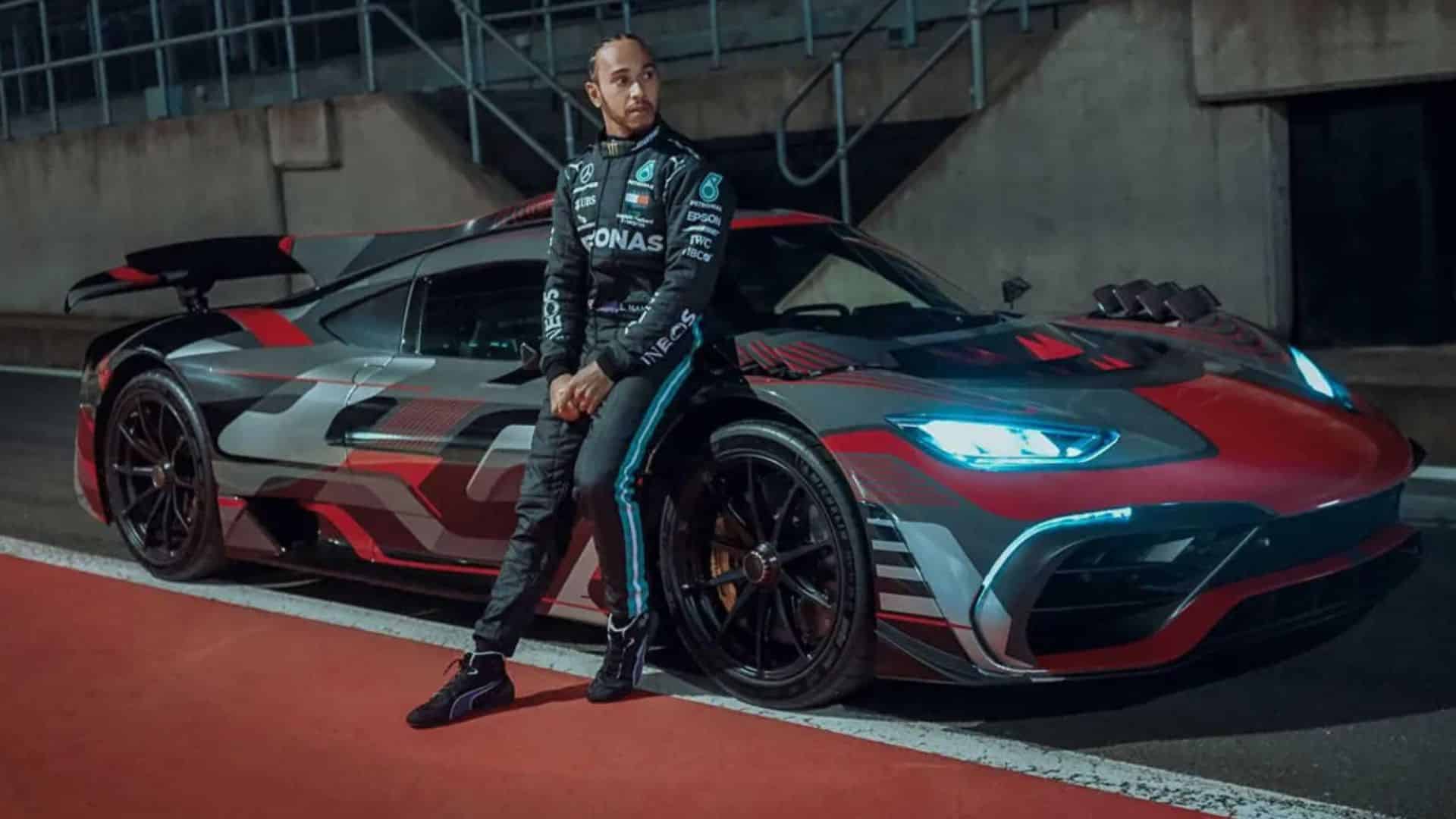 Lewis Hamilton posing beside a custom Mercedes-AMG hypercar on a racetrack at night