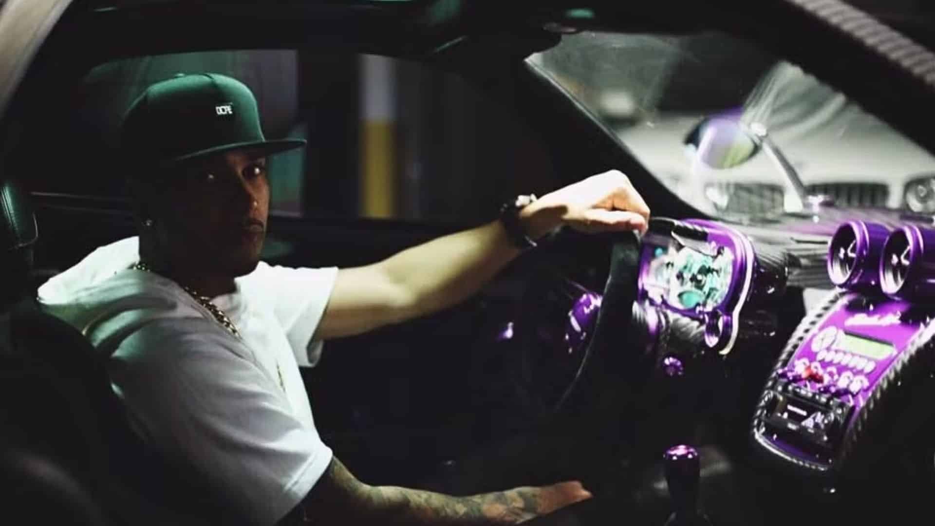 Lewis Hamilton sitting inside a luxury sports car with a custom purple-lit interior at night