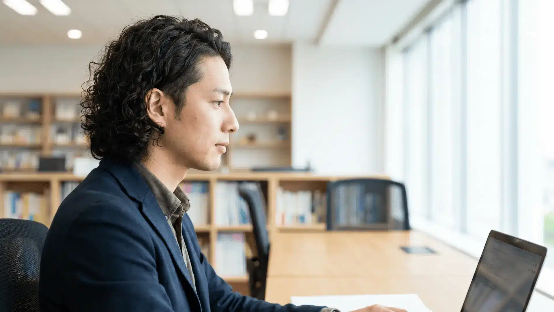Handsome male model in an office with loose curls, medium-length and kept away from the face