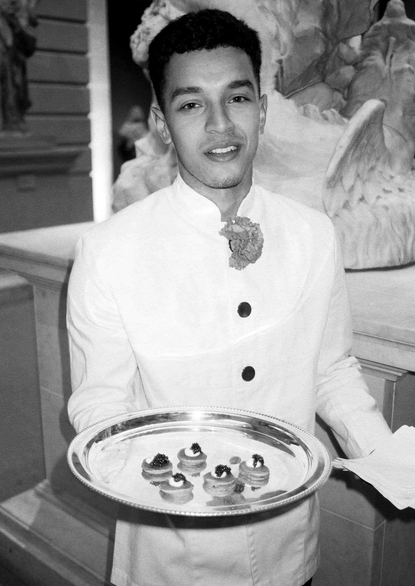 Luka Sabbat offering a tray of appetizers at the 2019 Met Gala, dressed in white (1)