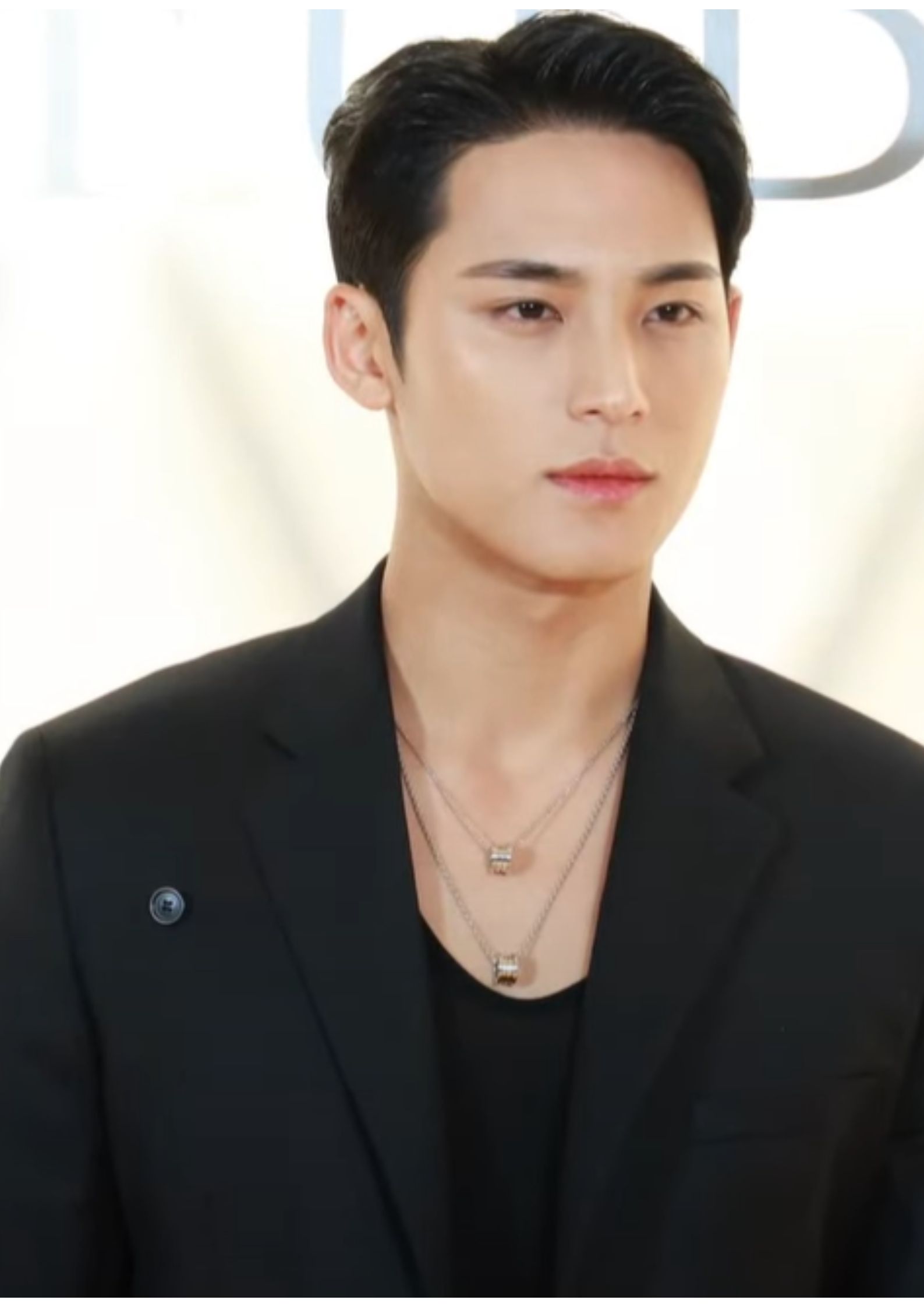 Mingyu from Seventeen in a black suit at an event, known for his height and stage presence
