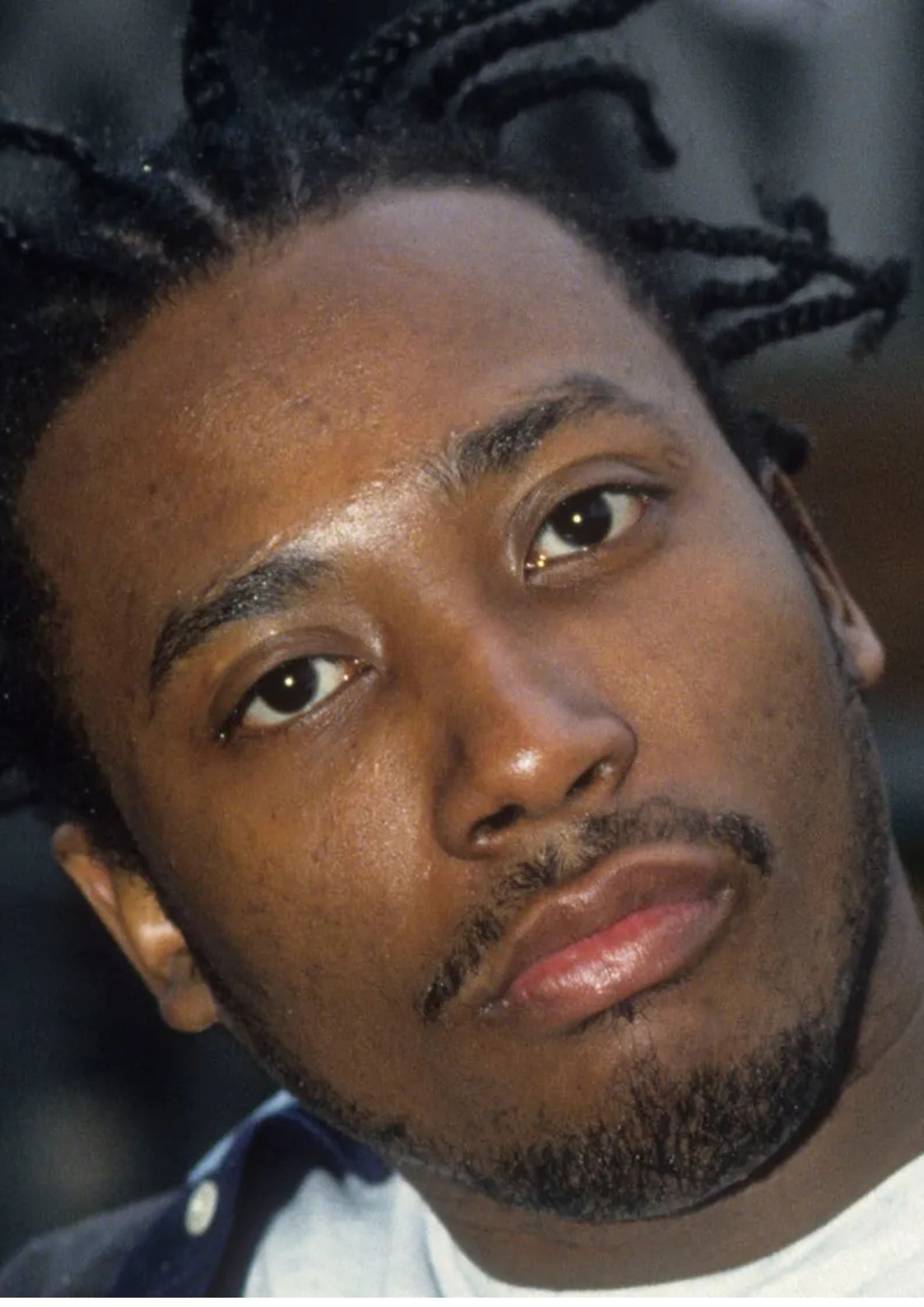 Ol' Dirty Bastard (Russell Tyrone Jones) from Wu-Tang Clan with braided hair, wearing a dark jacket and white shirt, looking at the camera