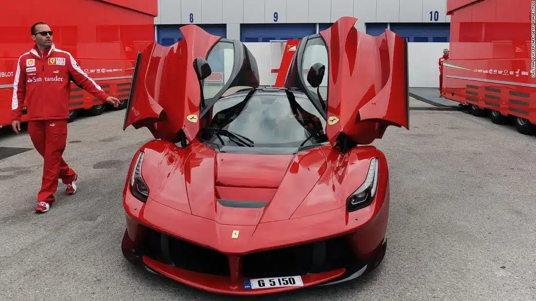 Red Ferrari LaFerrari with butterfly doors open parked in a Formula 1 paddock area