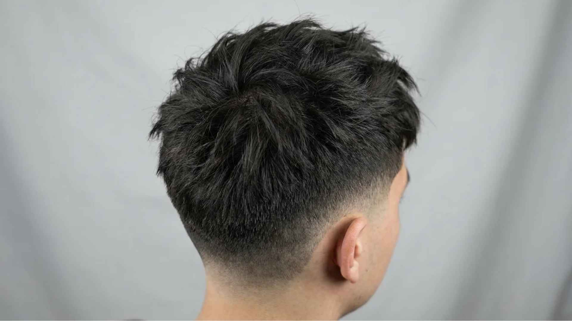 Textured crop with short choppy layers on top blending into a clean skin fade.