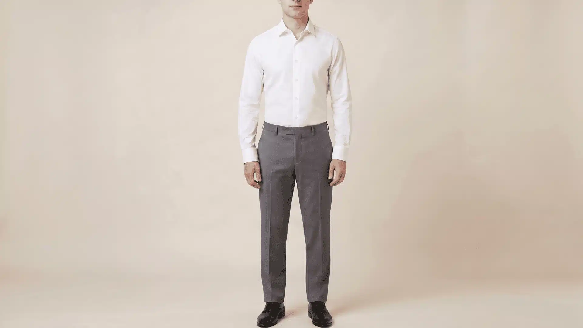 Man wearing a white long-sleeve shirt with charcoal grey pants and black shoes, standing in a neutral background.
