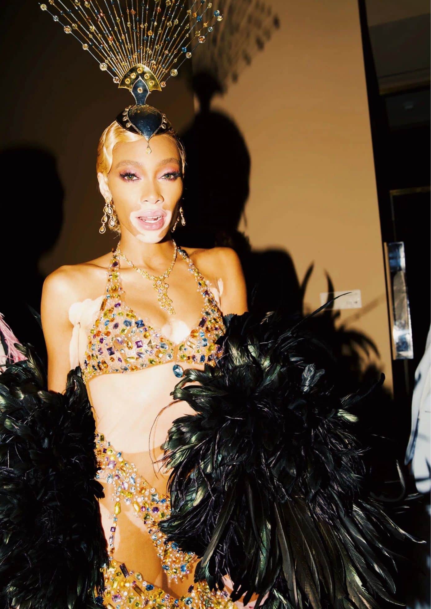 Winnie Harlow in a jeweled outfit with feathered accessories and a peacock-inspired headpiece. (1)