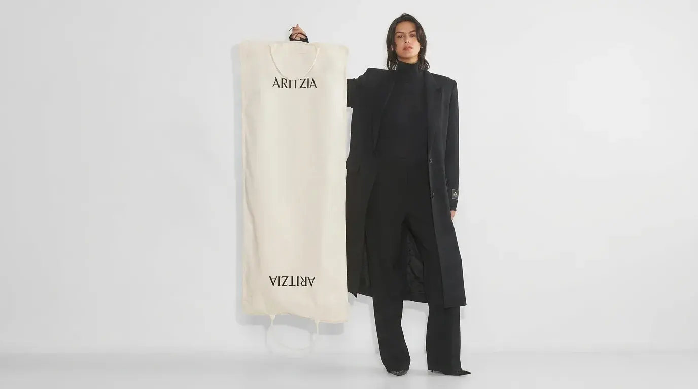 Woman holding an Aritzia garment bag.
