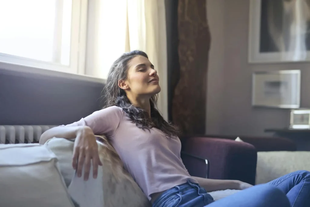 Woman relaxing on a beige sofa in a sunlit living room