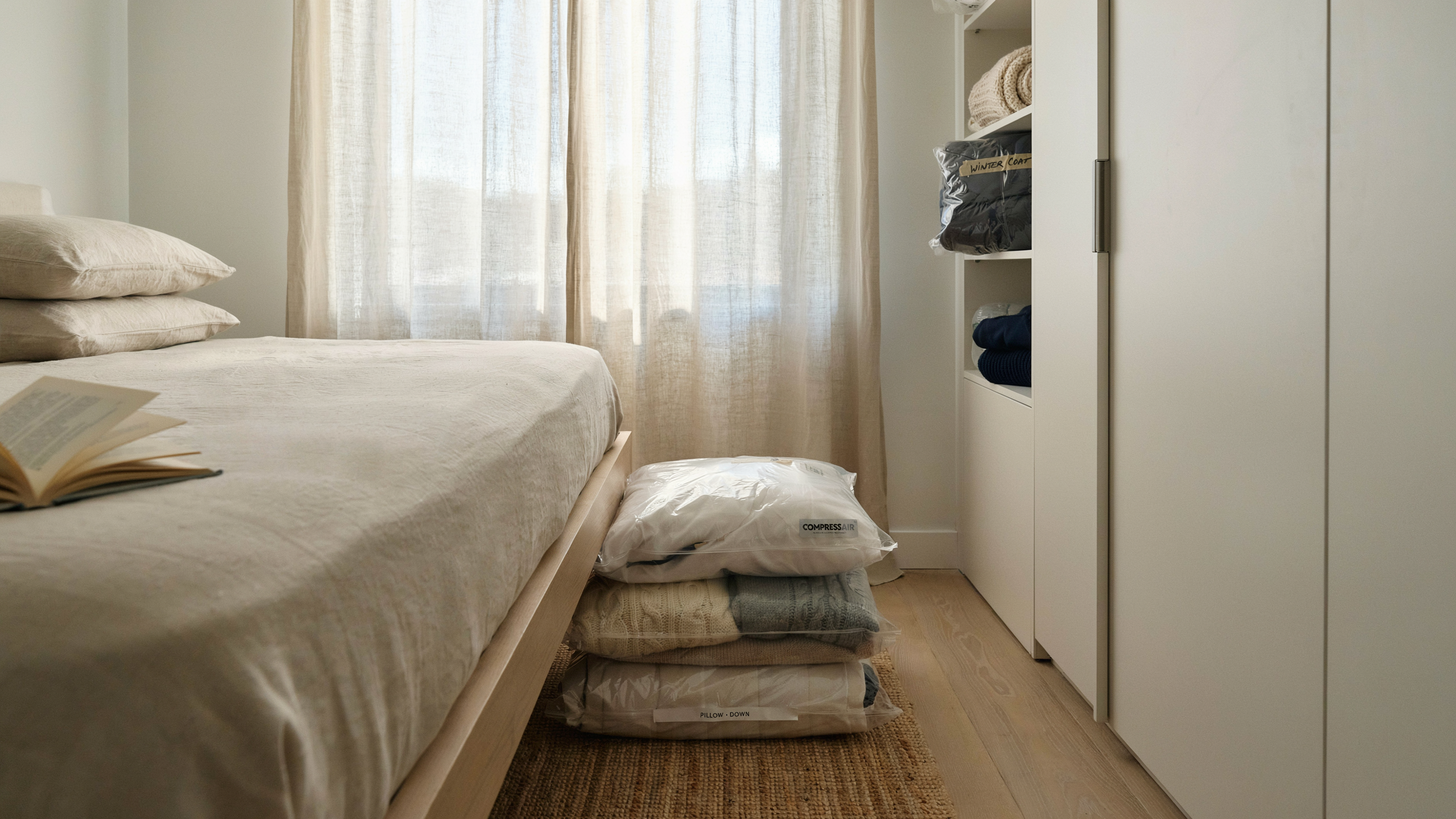 Under-bed vacuum storage bags neatly compressing seasonal items, bedroom uncluttered, neutral colors, realistic and tidy setup.
