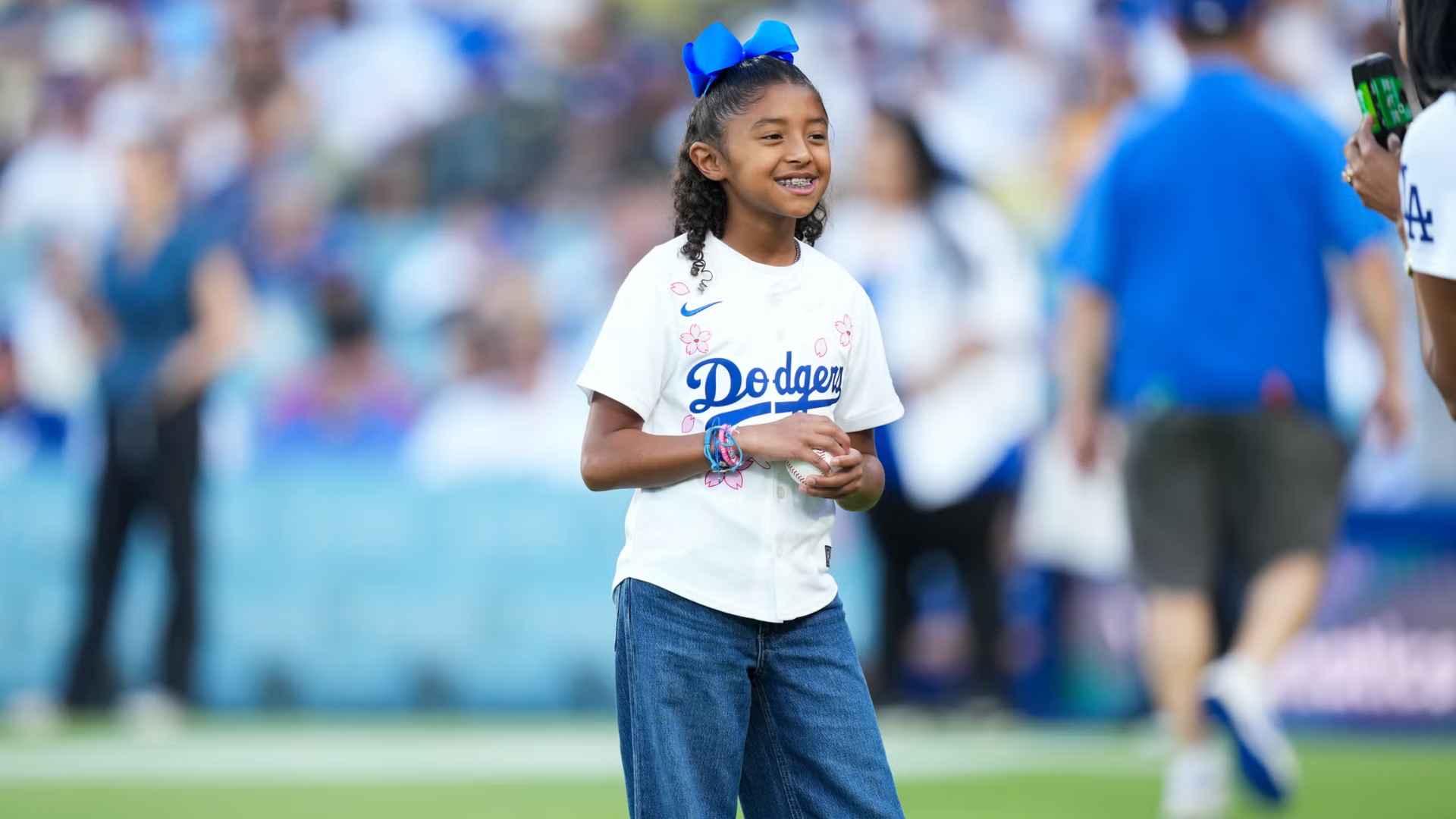 Gianna Bryant smiling on field wearing Dodgers shirt and blue hair bow