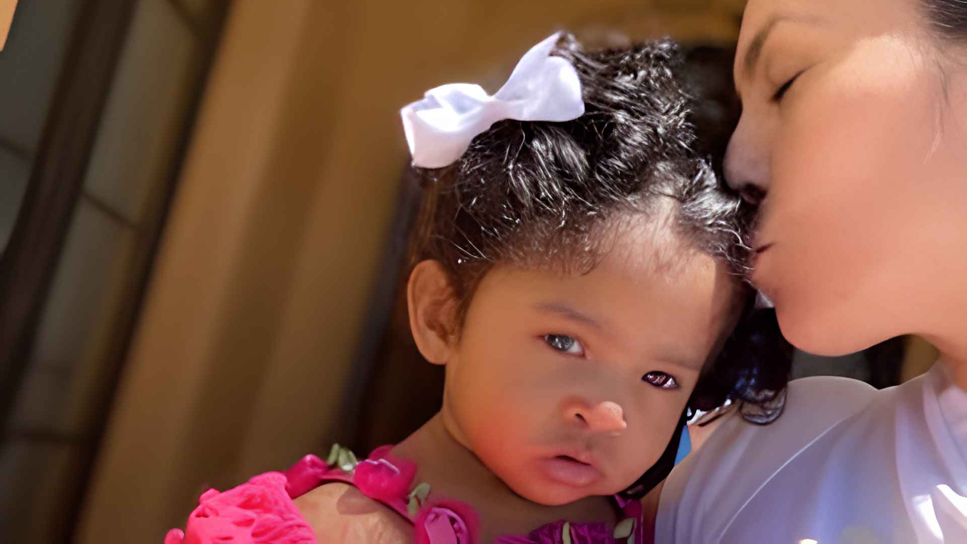 Vanessa Bryant kissing youngest daughter Capri, girl wearing pink dress with white bow